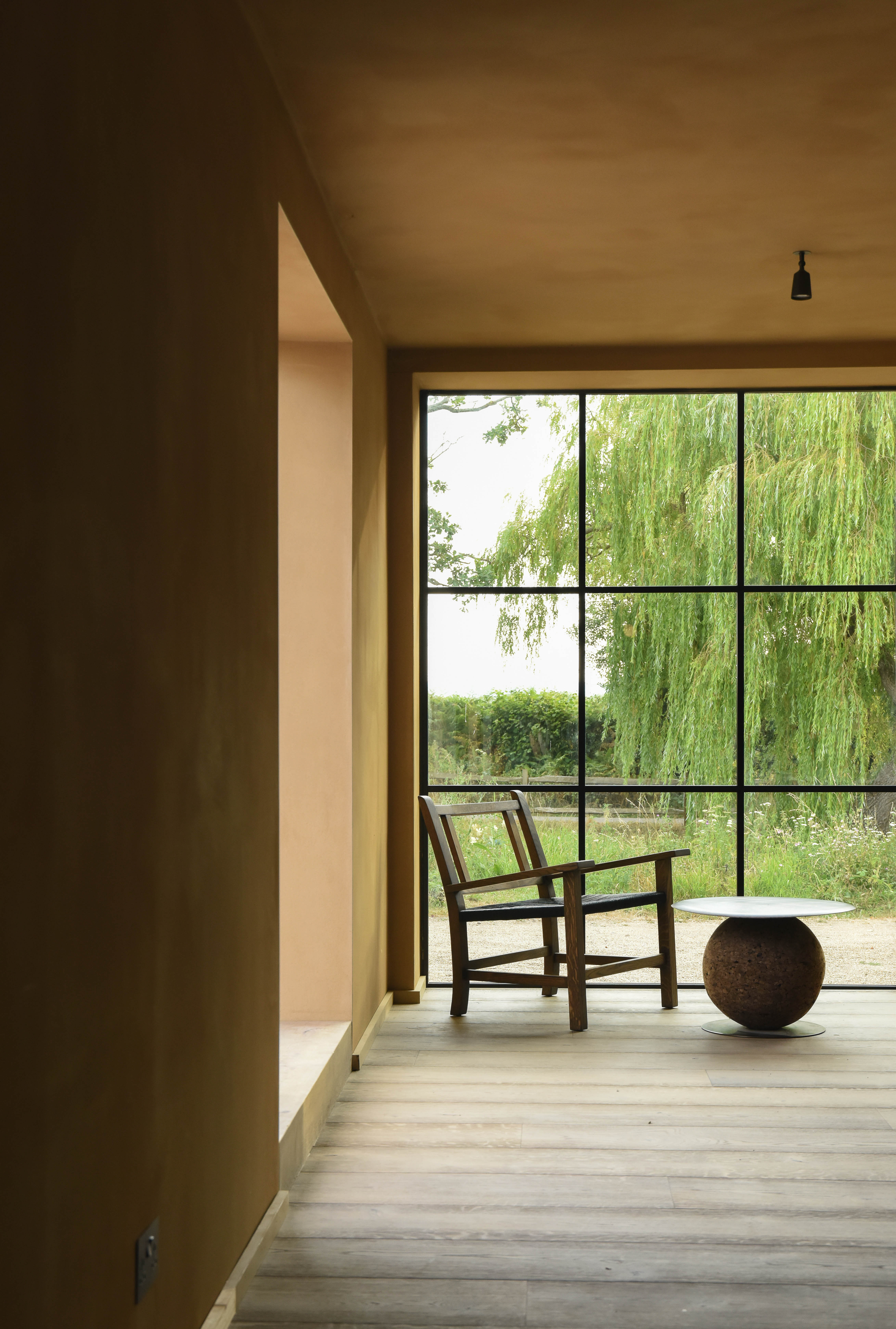 The glass-fronted studio link, chair and cork table framed by the willow